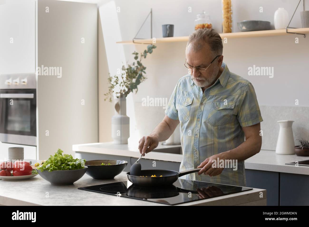 Buon uomo di mezza età che cucina cibo in cucina. Foto Stock