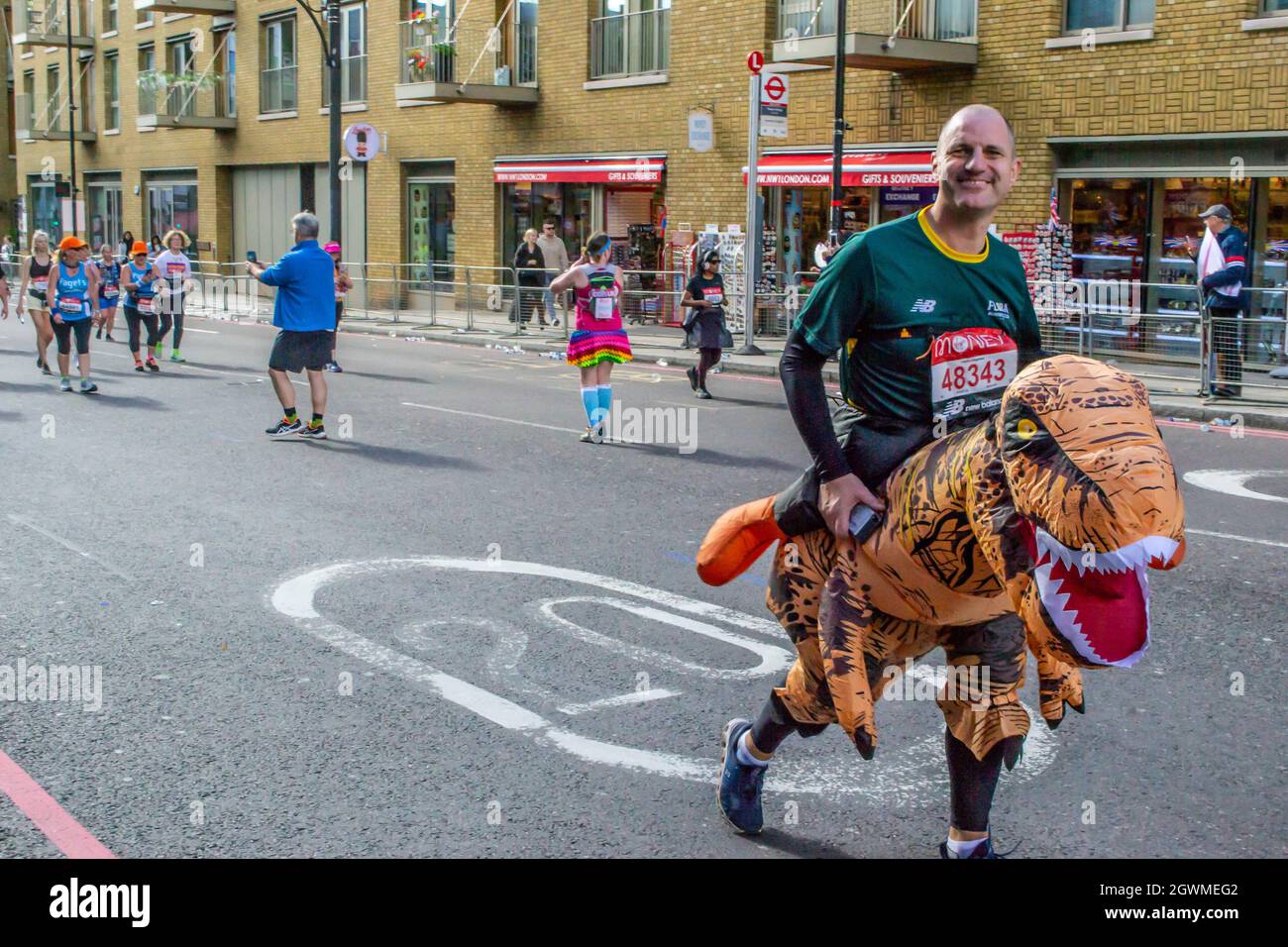 TOWER BRIDGE, LONDRA, INGHILTERRA - 03 ottobre 2021: Uomo che indossa un costume da dinosauro alla Maratona di Londra Virgin Money Foto Stock