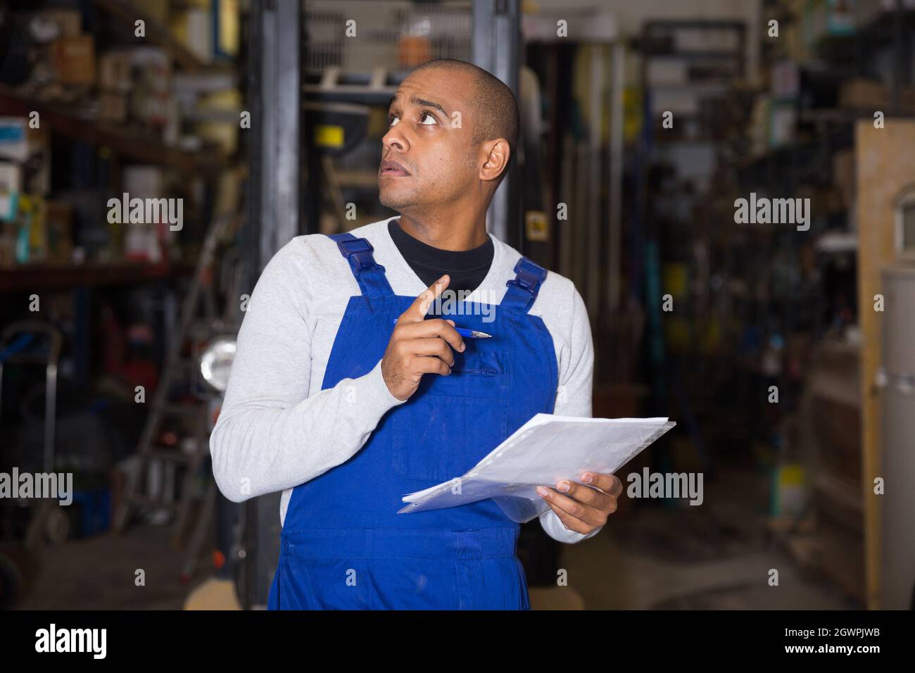 Addetto al magazzino che prende appunti durante l'inventario dei materiali da costruzione Foto Stock