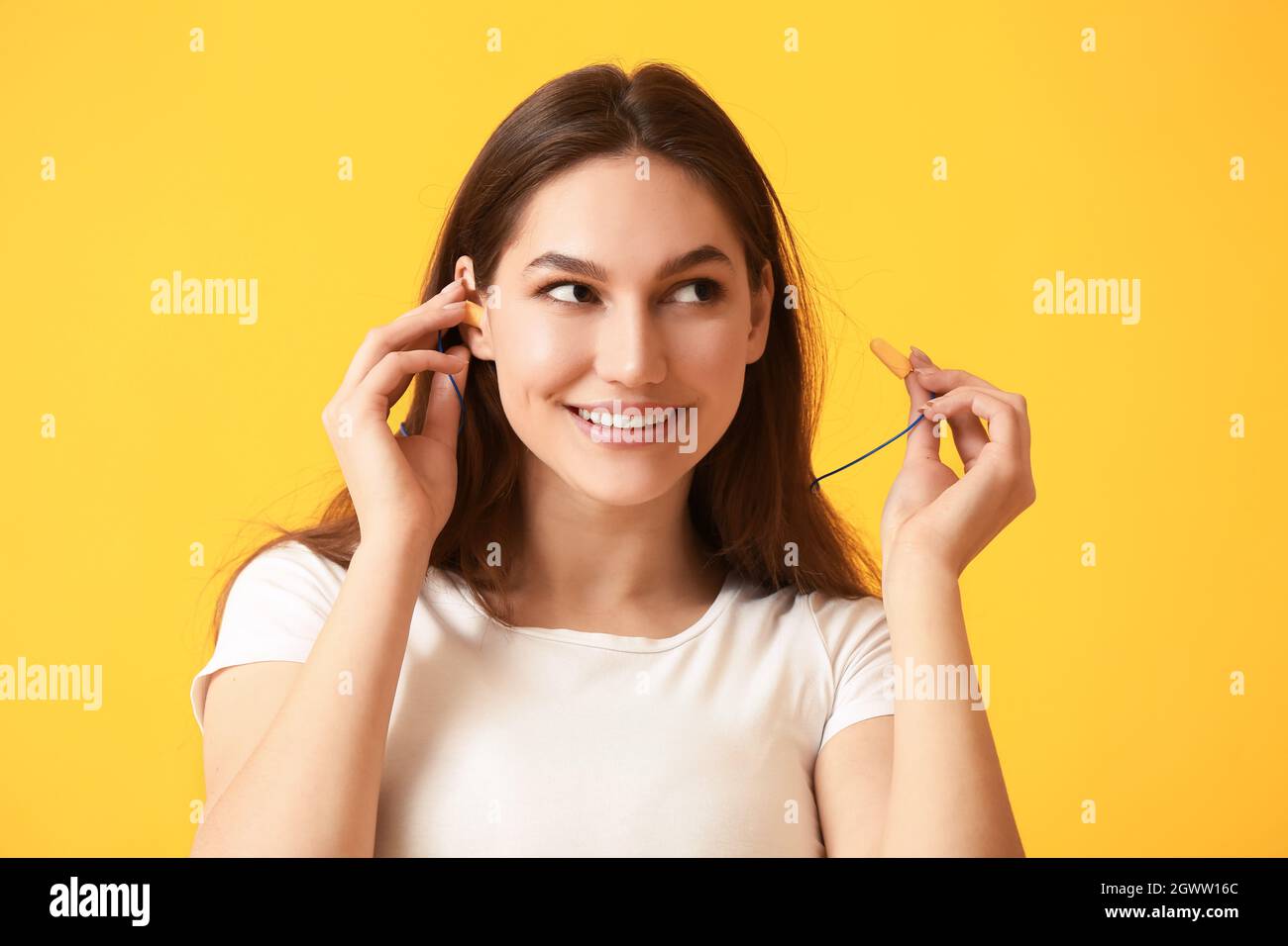 Bella giovane donna con tappi per le orecchie su sfondo giallo Foto stock -  Alamy