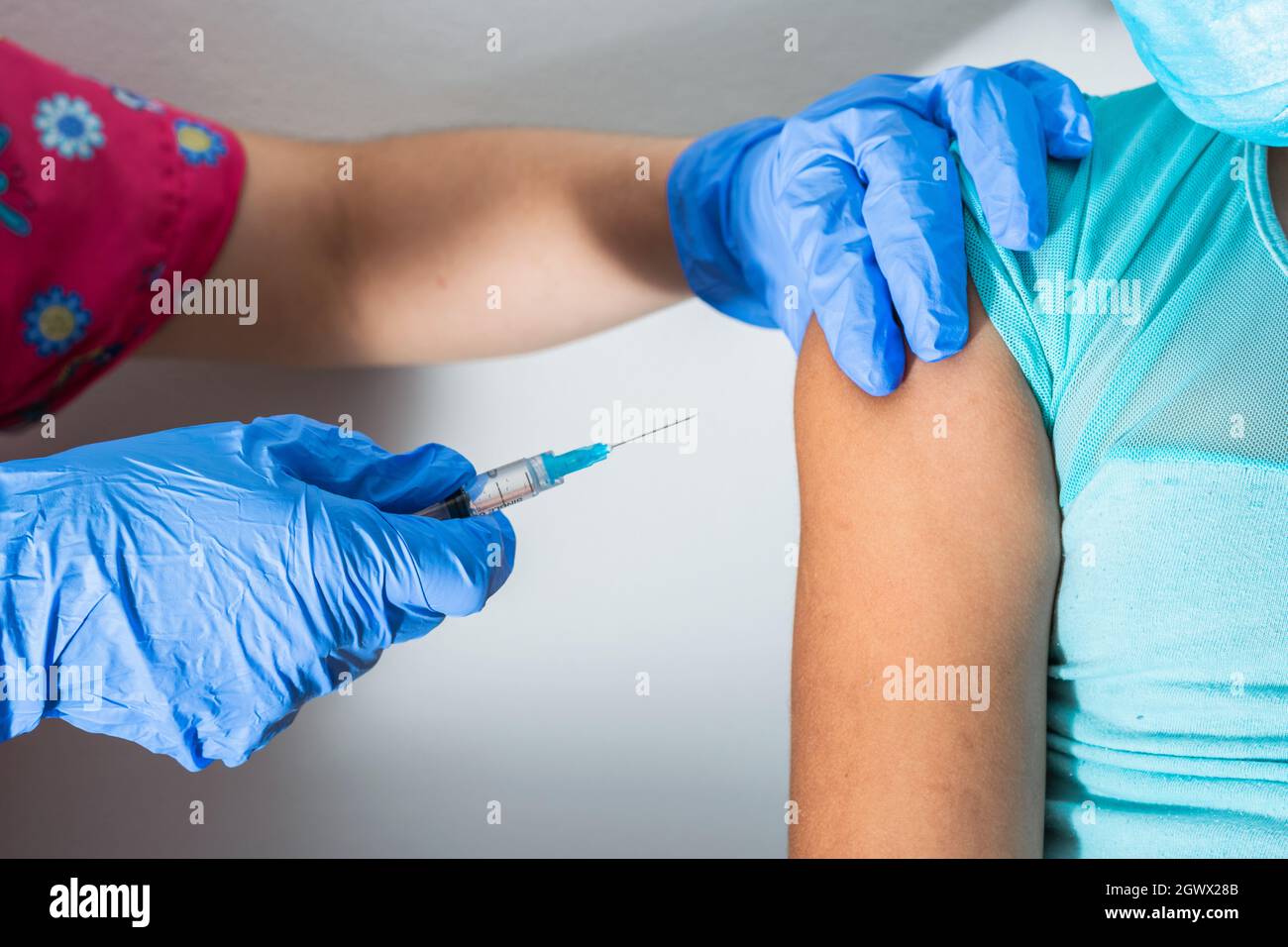 l'infermiere dei bambini inietta il braccio di bambina marrone, le mani del medico con i guanti di gomma che iniettano il covid-19 o il vaccino di flu. medico, salute e pandemic Foto Stock