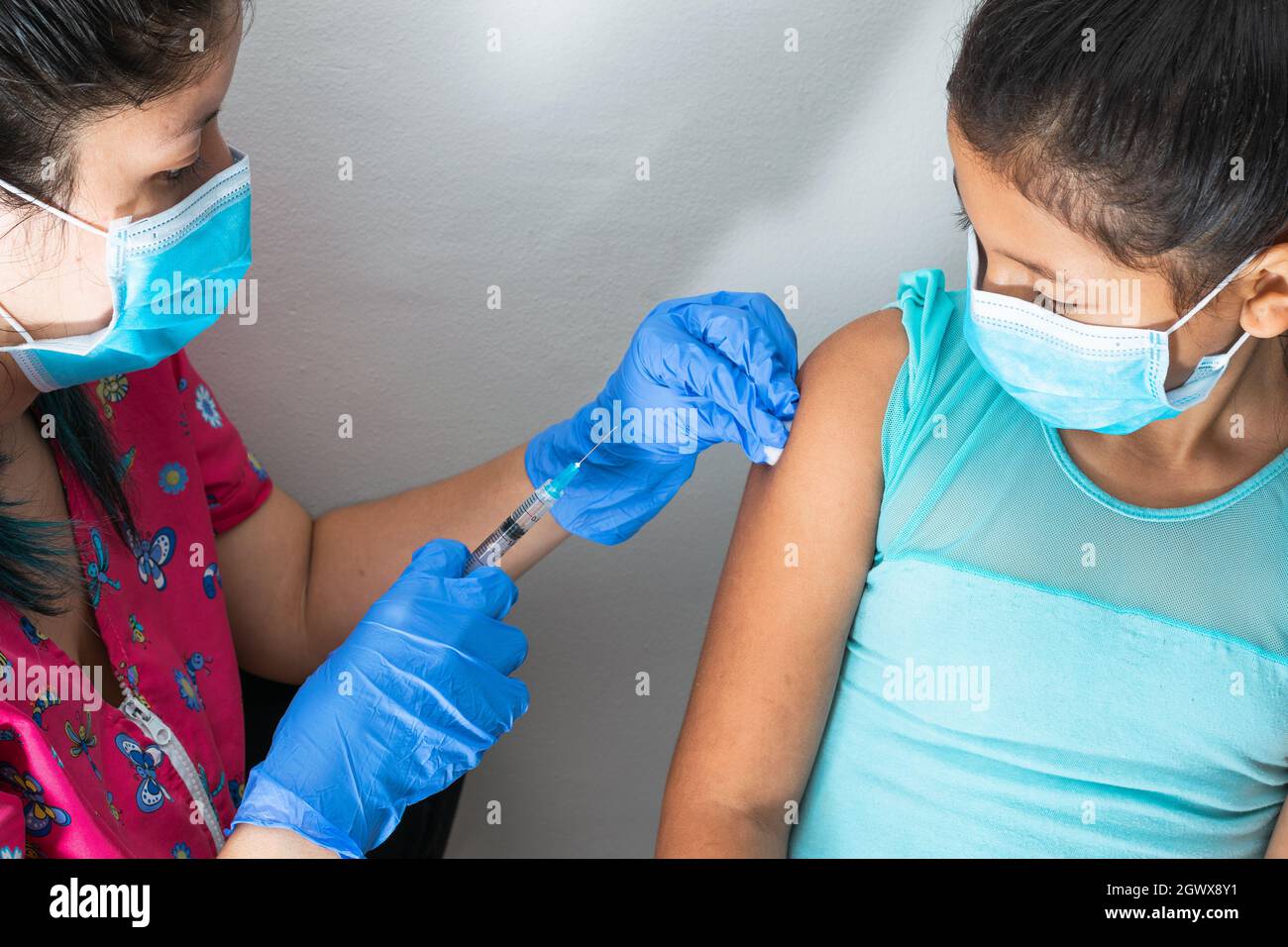 l'infermiera dei bambini che inietta il braccio della ragazza marrone. medico che inietta il vaccino del covid-19. vaccino della schivazione della ragazza, colpo di flu. concetto medico, salute e pandemic. Foto Stock