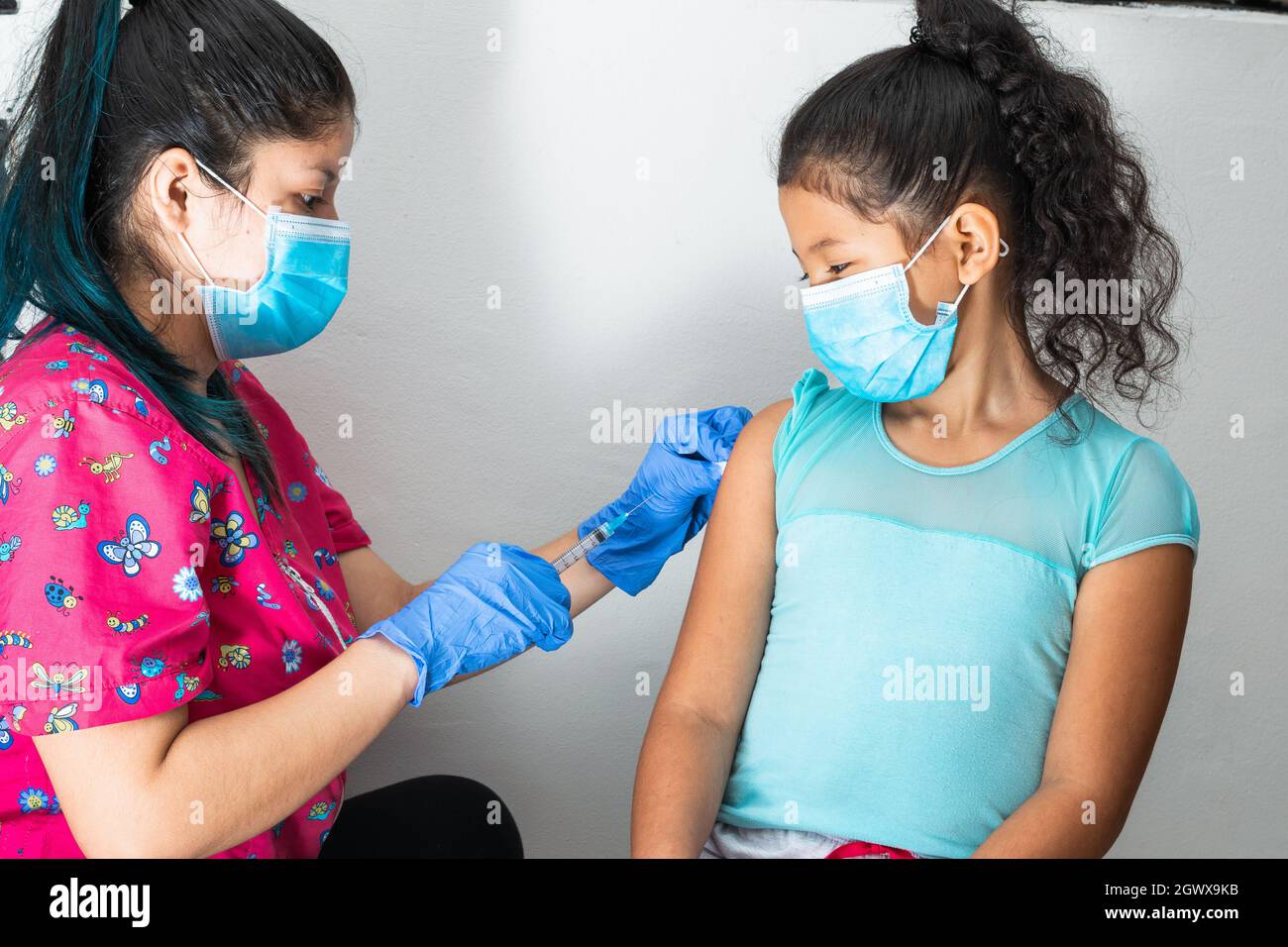 infermiera per bambini disinfezione del braccio di una ragazza marrone prima di somministrare l'iniezione. medico che inietta il vaccino covid-19. vaccino influenzale. concetto medico, salute Foto Stock