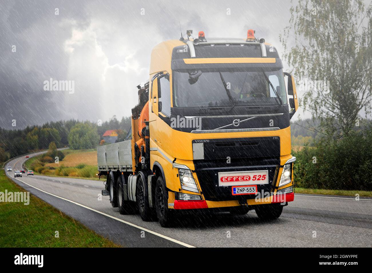 Camion giallo Volvo FH per la costruzione con Effer 525 camion montato gru su strada in una giornata piovosa in autunno. Salo, Finlandia. Settembre 24, 2021. Foto Stock