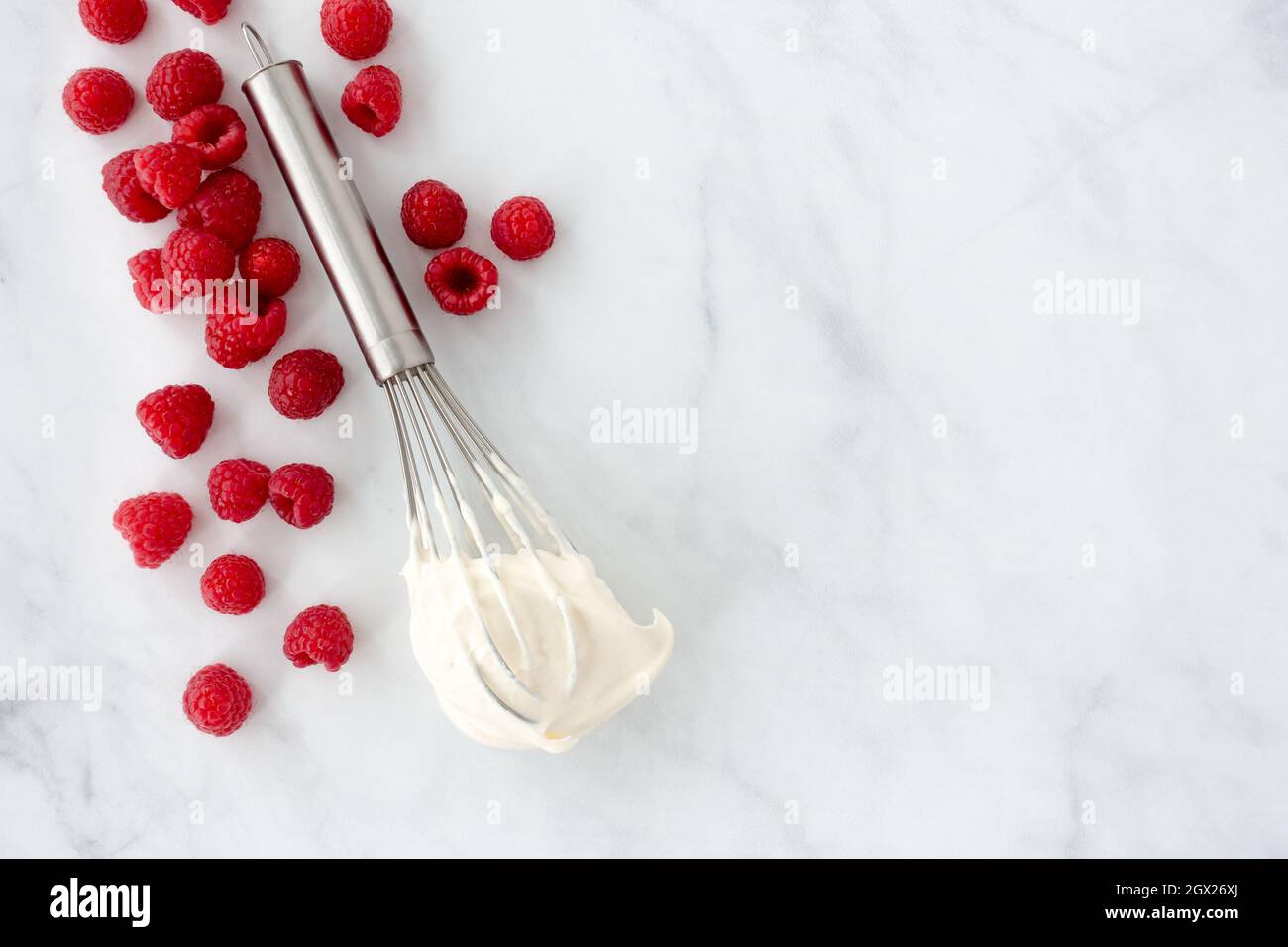 Lamponi e una frusta con panna montata su sfondo di marmo bianco e molto spazio per le copie. Vista dall'alto. Foto Stock