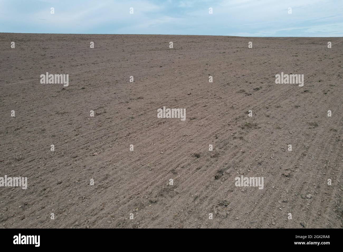 Terreno coltivato crudo marrone su sfondo cielo blu Foto Stock