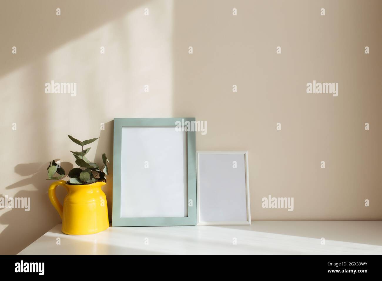 Cornici bianche vuote sul tavolo bianco all'interno con pareti beige vicino  alla finestra Foto stock - Alamy