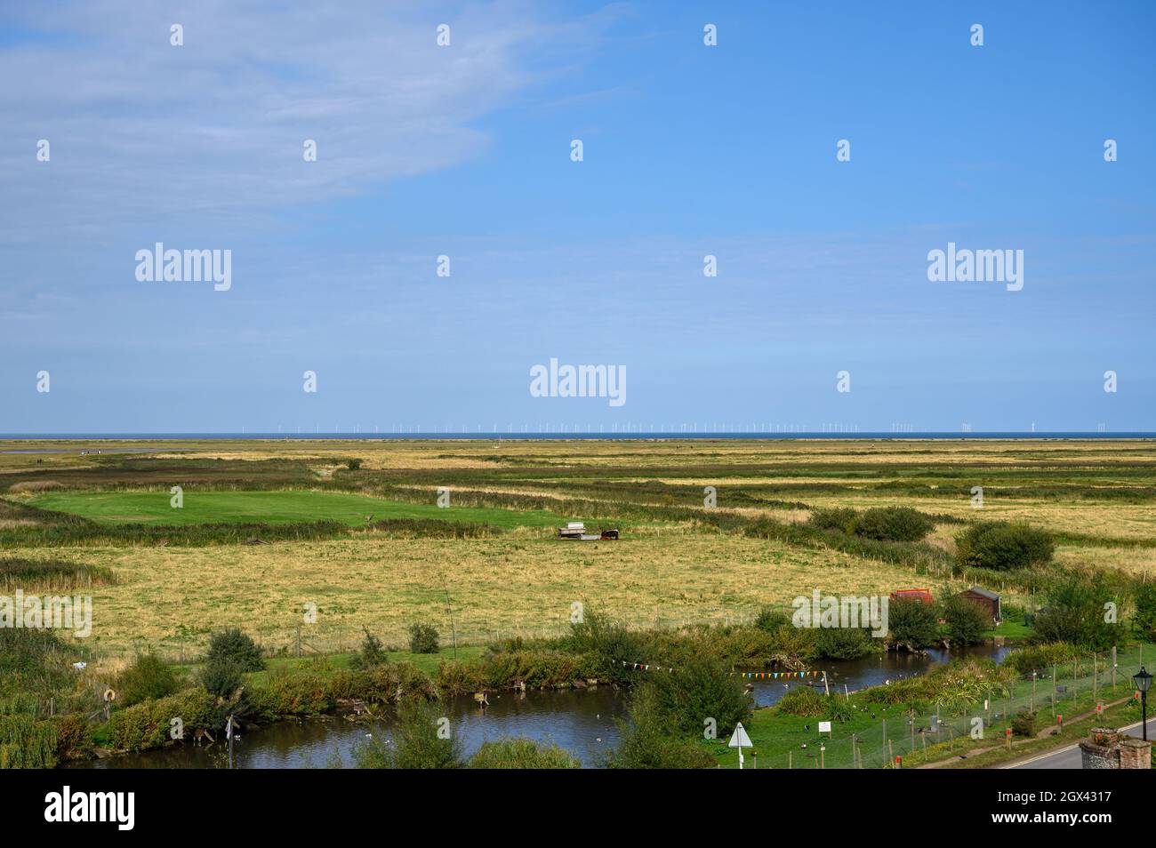 Vista sulle paludi di Blakeney Freshes e la Race Bank Wind Farm in lontananza sull'orizzonte del Mare del Nord, Norfolk, Inghilterra. Foto Stock