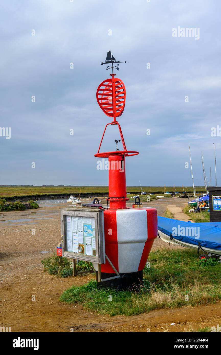 Una boa con wether vane e un pannello informativo per la Blakeney Harbour Association a Blakeney Freshes, Norfolk, Inghilterra. Foto Stock