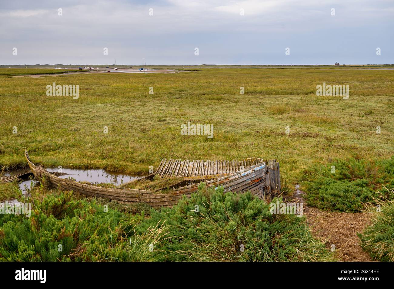 Il relitto erodente di una barca di legno posata per riposare sulla palude della Riserva Naturale Naturale di Blakeney, Norfolk, Inghilterra. Foto Stock
