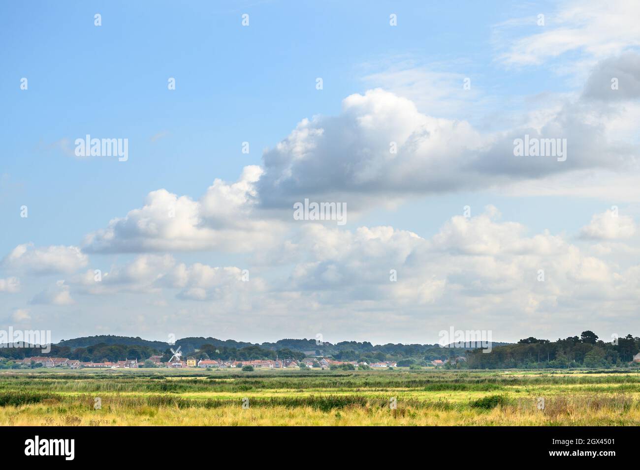 Vista di Cley vicino al villaggio del mare dal percorso a piedi a Blakeney Freshes con cielo grande e blu e le nuvole bianche fluffy, Norfolk, Inghilterra. Foto Stock