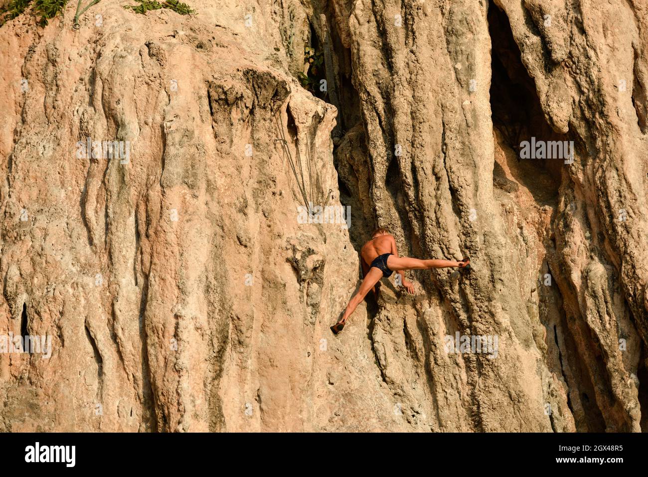 Un vecchio scalatore di roccia senza una rete appesa sulla scogliera con le mani. Rai Leh o Railay, Phra Nang Beach, Krabi, Thailandia. Sport, estremo. Foto Stock