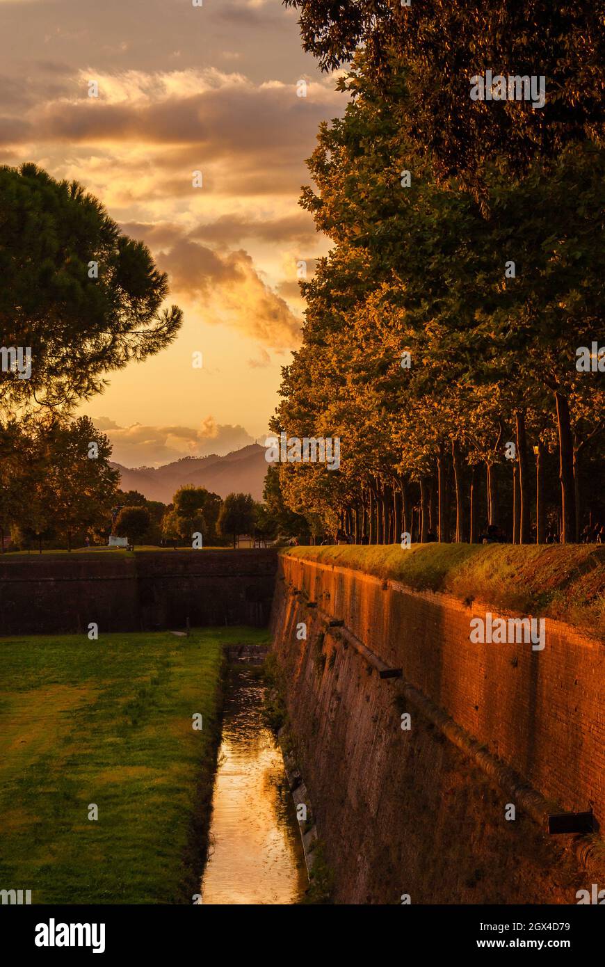 Lucca antiche mura parco con fossato con luce del tramonto Foto Stock