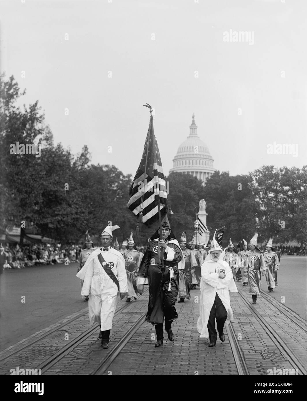 Foto d'epoca del 13 settembre 1926 che mostra i membri del Ku Klux Klan vestiti in abiti che passavano lungo Pennsylvania Avenue a Washington, D.C. con la bandiera a stelle e a strisce e la cupola del Campidoglio sullo sfondo Foto Stock