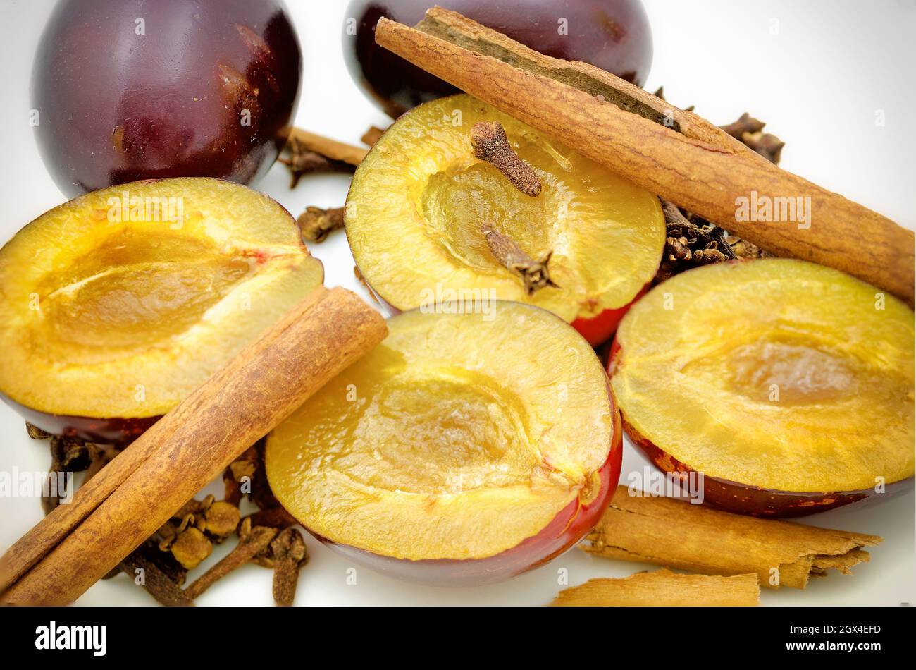 metà di susine succose, bastoncini di cannella e chiodi di garofano Foto Stock