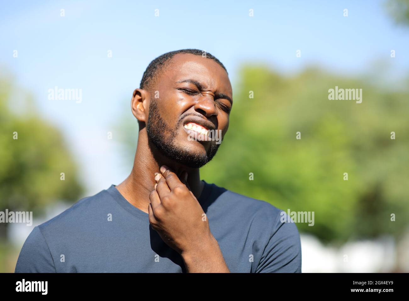 L'uomo nero si lamenta del mal di gola in un parco Foto Stock