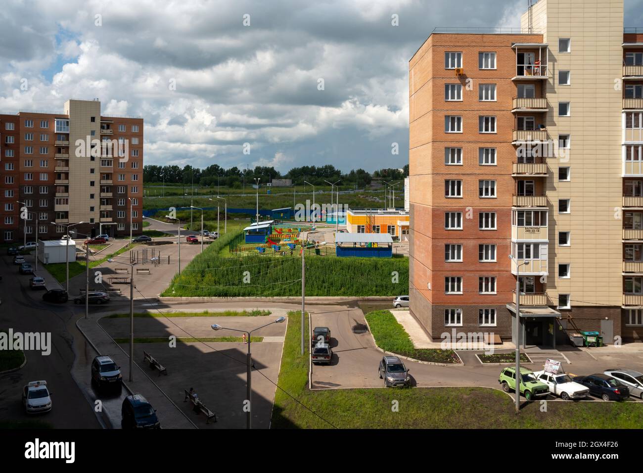 Vista dall'alto di un cortile comune di edifici di appartamenti con auto parcheggiate sul marciapiede in una giornata estiva. Foto Stock