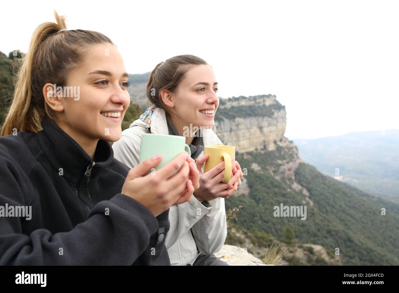 Due escursionisti felici bere caffè e contemplare in una scogliera Foto Stock