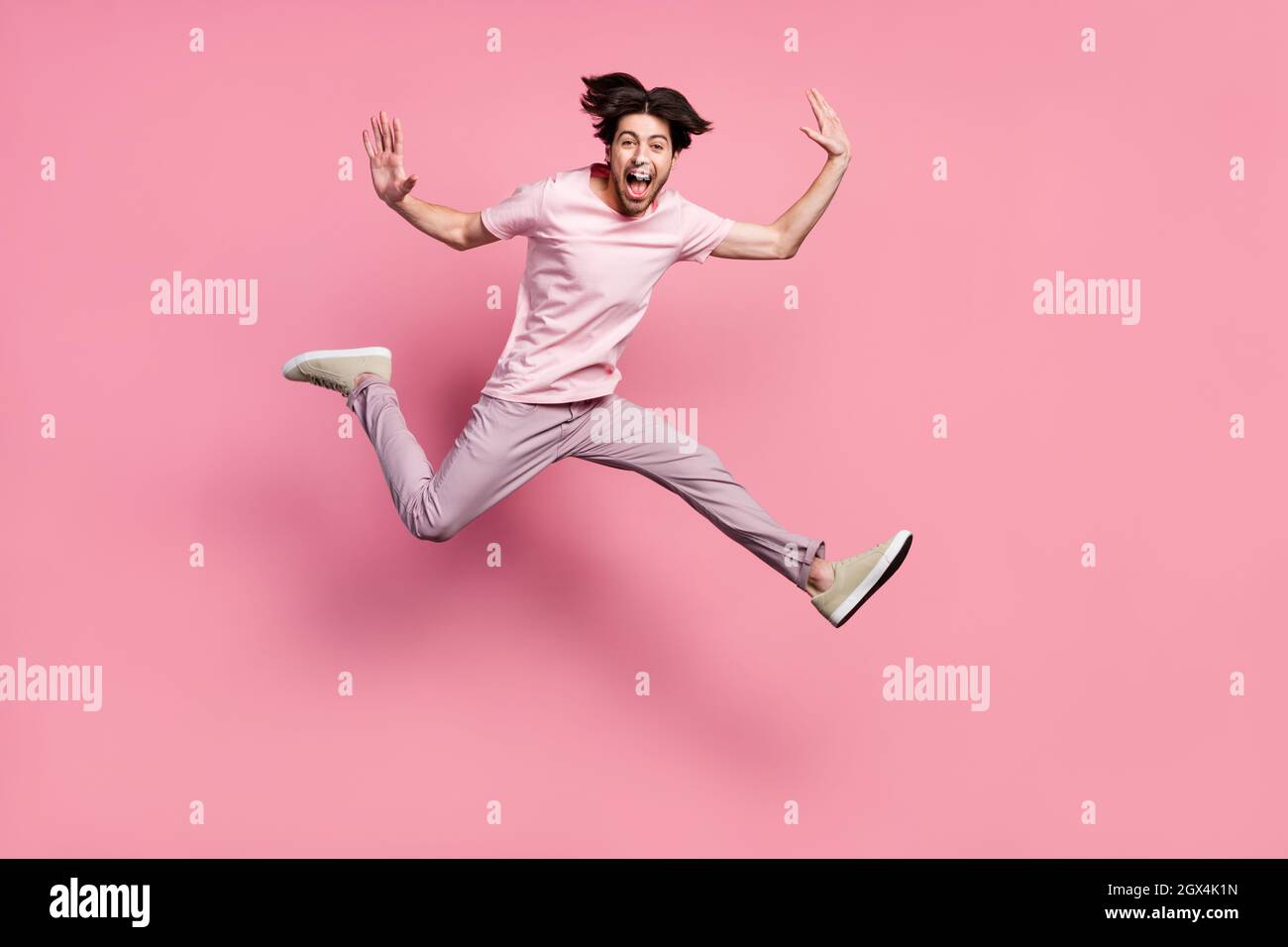Uomo di dimensioni del corpo a tutta lunghezza che indossa abiti casual che salta su ridendo isolato colore rosa pastello sfondo Foto Stock