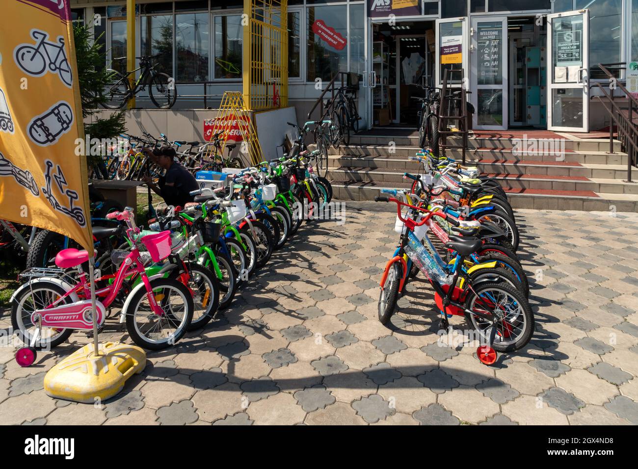 Le biciclette per bambini sono esposte in vendita e noleggiate sul marciapiede di fronte al negozio in una giornata estiva. Foto Stock