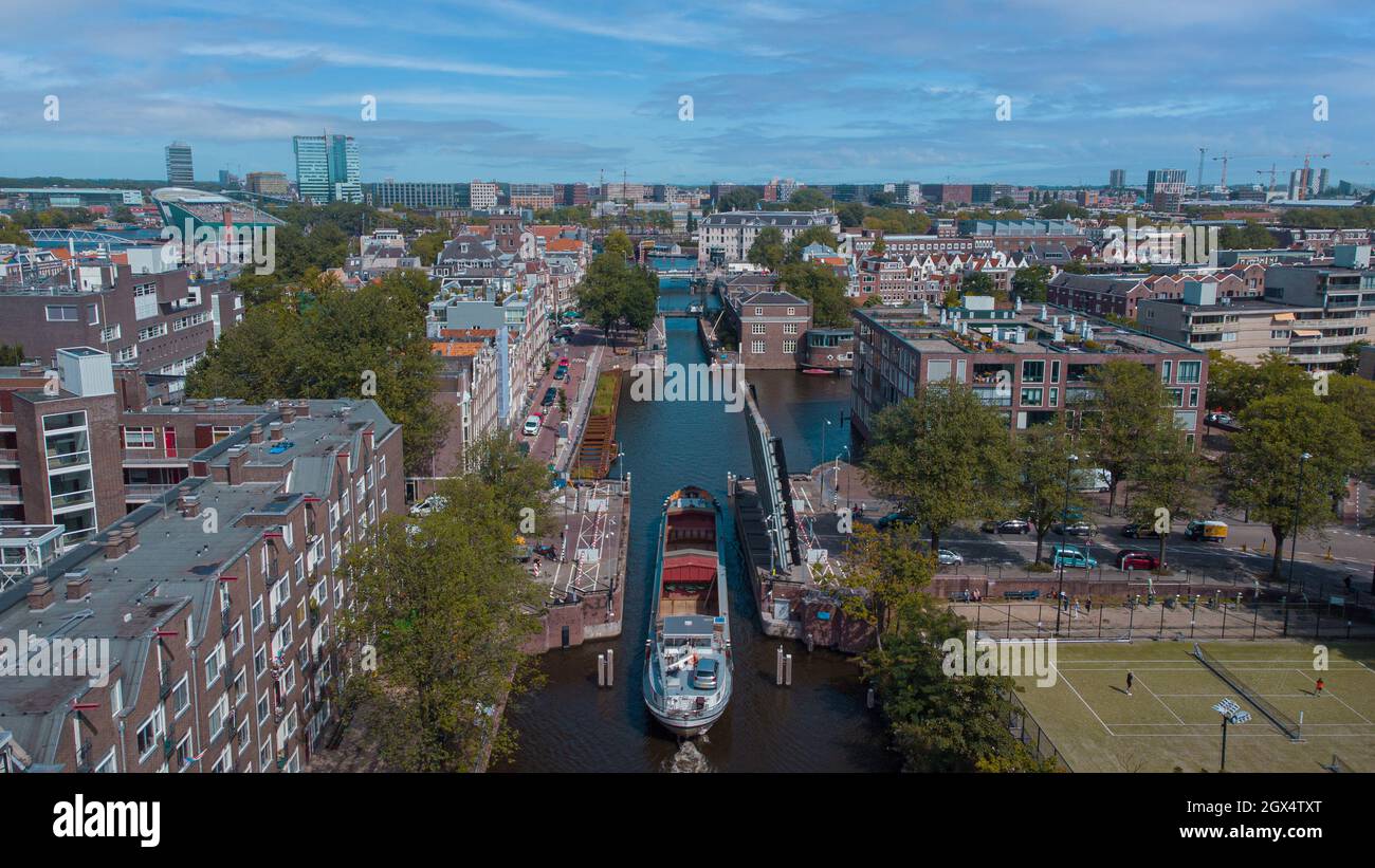 Vista aerea del drone di una nave che passa attraverso il ponte stradale nel canale di amsterdam. Spedire sotto il ponte aperto sul canale. Foto Stock