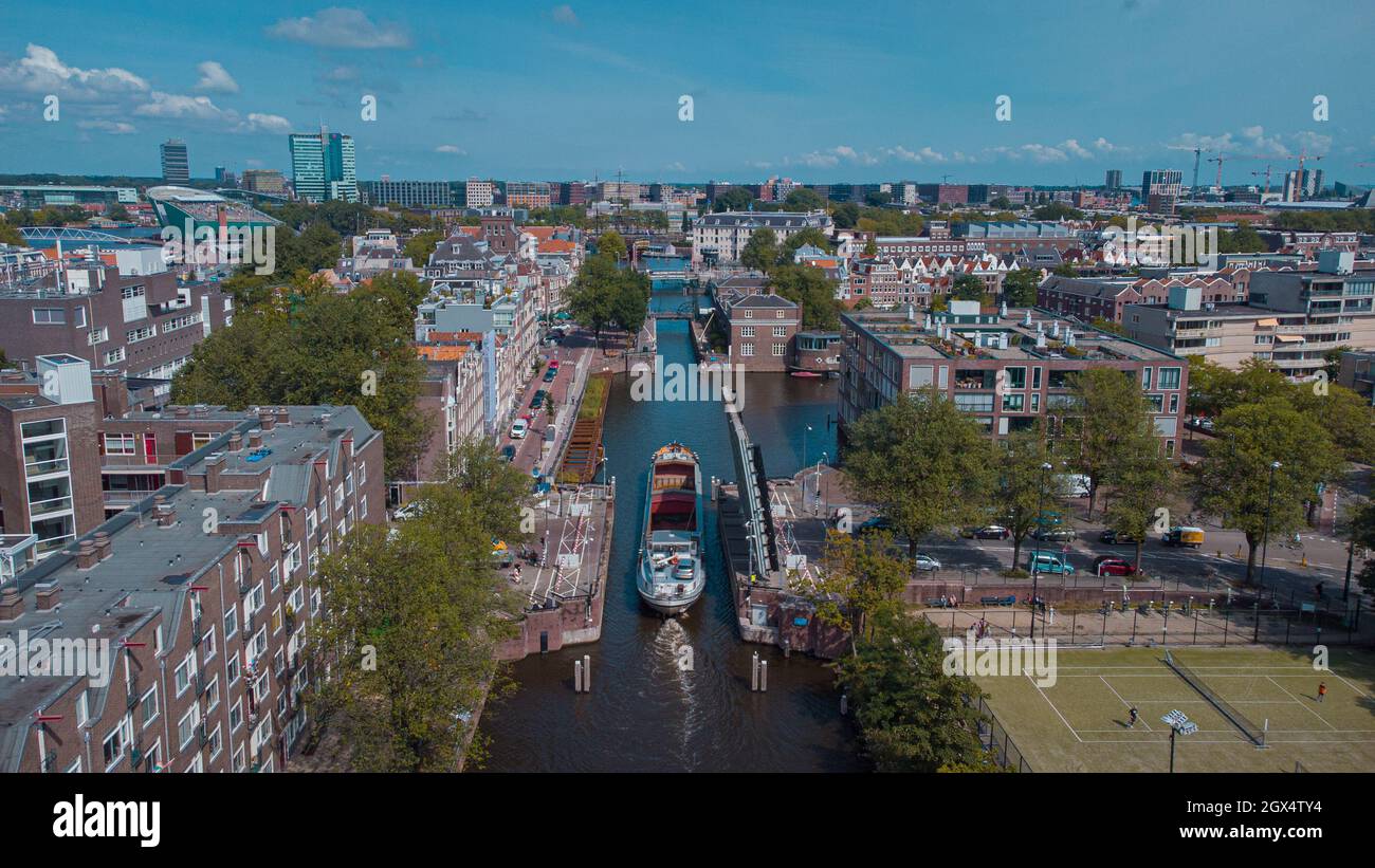 Vista aerea del drone di una nave che passa attraverso il ponte stradale nel canale di amsterdam. Spedire sotto il ponte aperto sul canale. Foto Stock