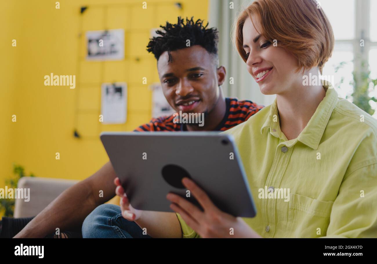 Giovane coppia biraciale con tablet, divertirsi in casa, controllare i social network insieme. Foto Stock
