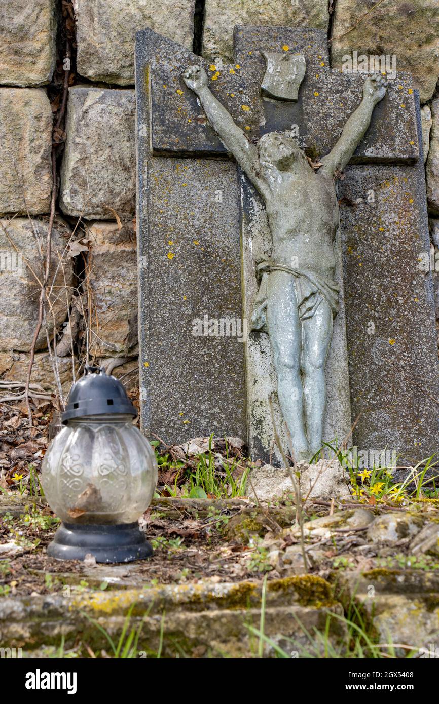 Lapide con Gesù crocifisso e lampada nel cimitero Foto Stock
