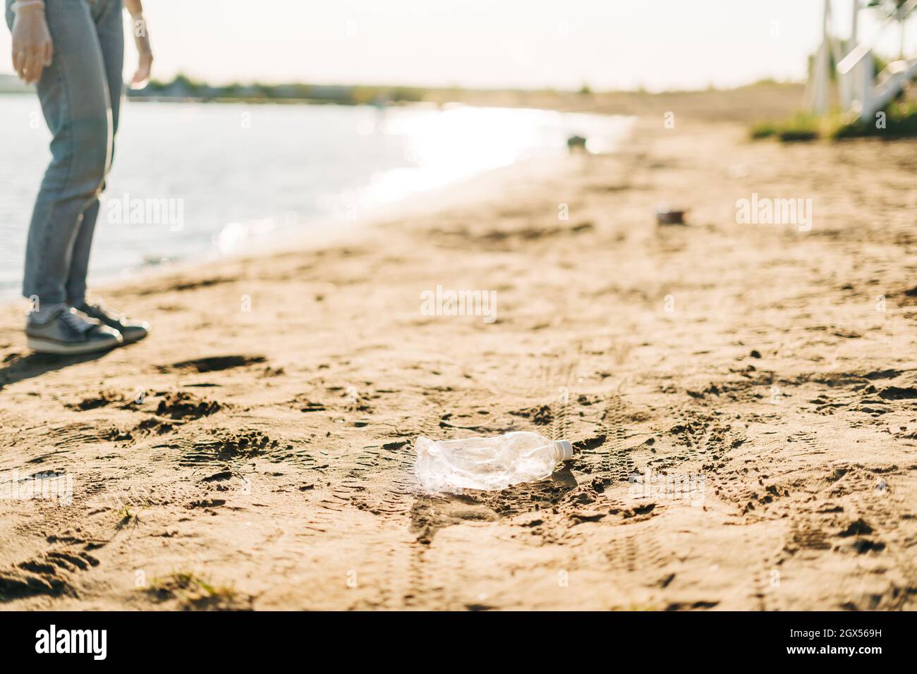 Bottiglia d'acqua di plastica usata lavata in su sulla riva di una spiaggia, evidenziando la crisi mondiale dell'inquinamento di plastica. Ecologia ambientale Foto Stock