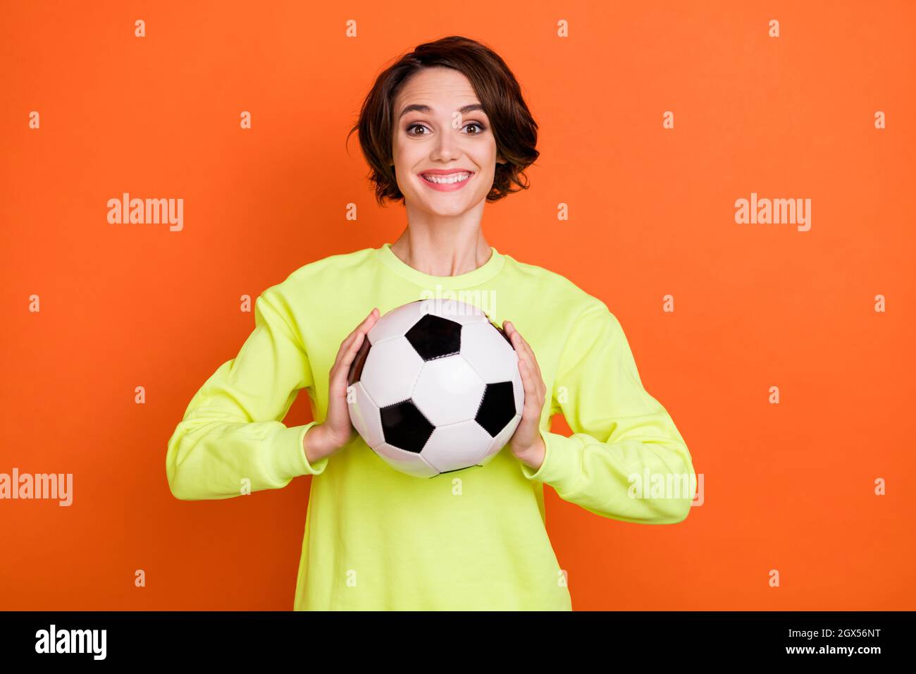 Ritratto di attraente ragazza allegra che tiene in mano palla lancio pass keeper isolato su sfondo di colore arancione chiaro Foto Stock