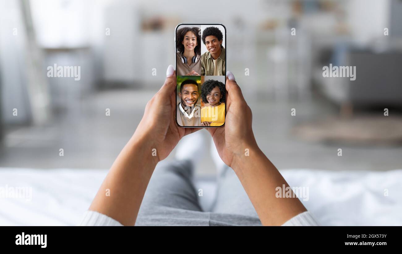 La millenaria donna afroamericana ritagliata riposa a casa e guarda lo schermo del telefono, doppia esposizione con i colpi di testa degli amici Foto Stock