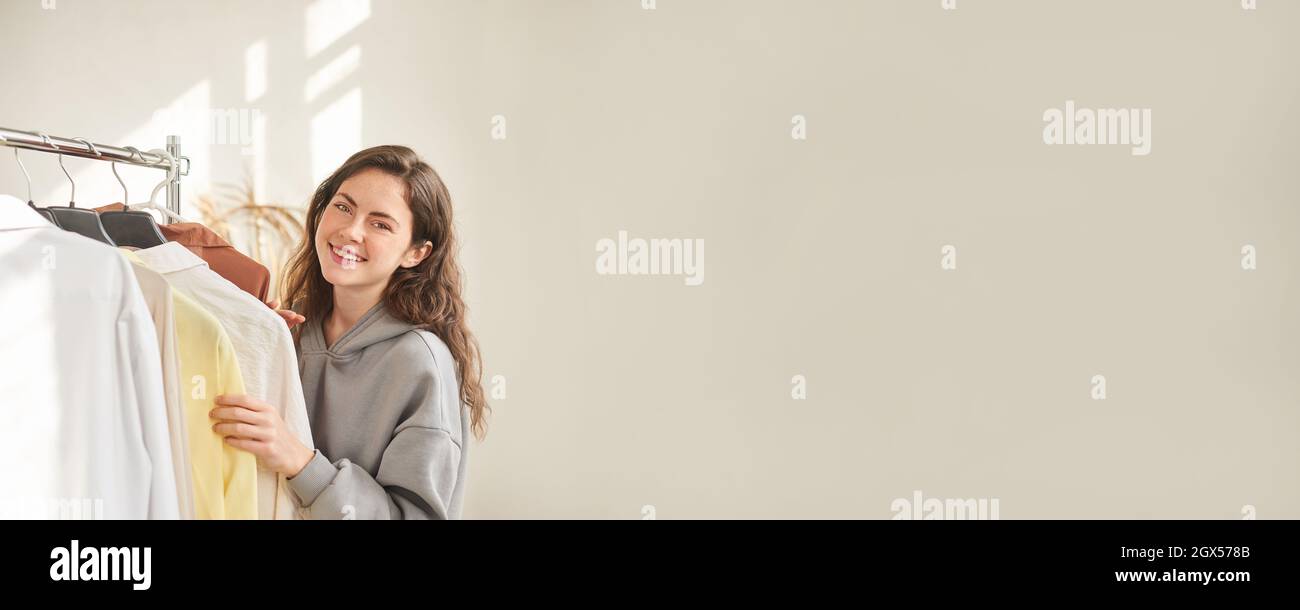 banner per negozio di abbigliamento. donna nel negozio sceglie abiti. venditore appende abiti su appendiabiti Foto Stock