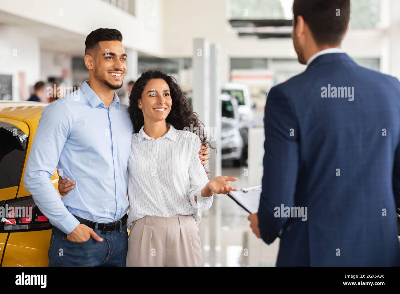 Felice famiglia arabic che acquista la nuova automobile, parlando con il responsabile di vendite Foto Stock