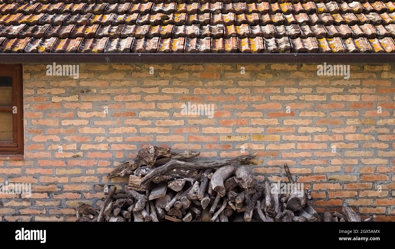 Tronchi di legno impilati di fronte ad un casale in mattoni e pietra (Umbria, Italia, Europa) Foto Stock