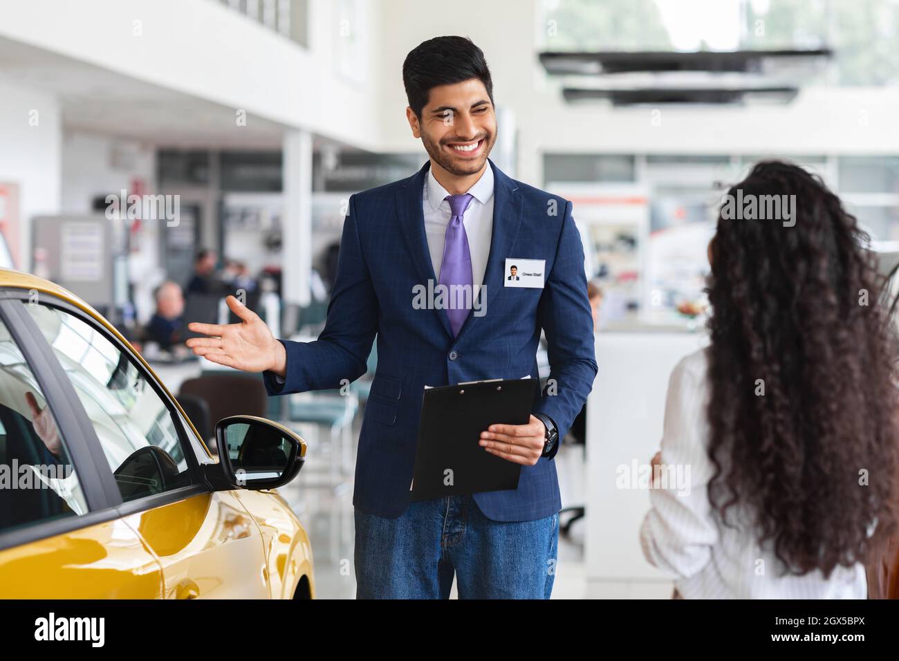 Signora mediorientale che sceglie la nuova automobile, avendo colloquio con il responsabile vendite Foto Stock