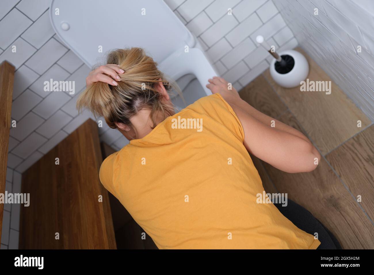 Donna che inchinava la testa sopra il gabinetto in bagno vista dall'alto Foto Stock