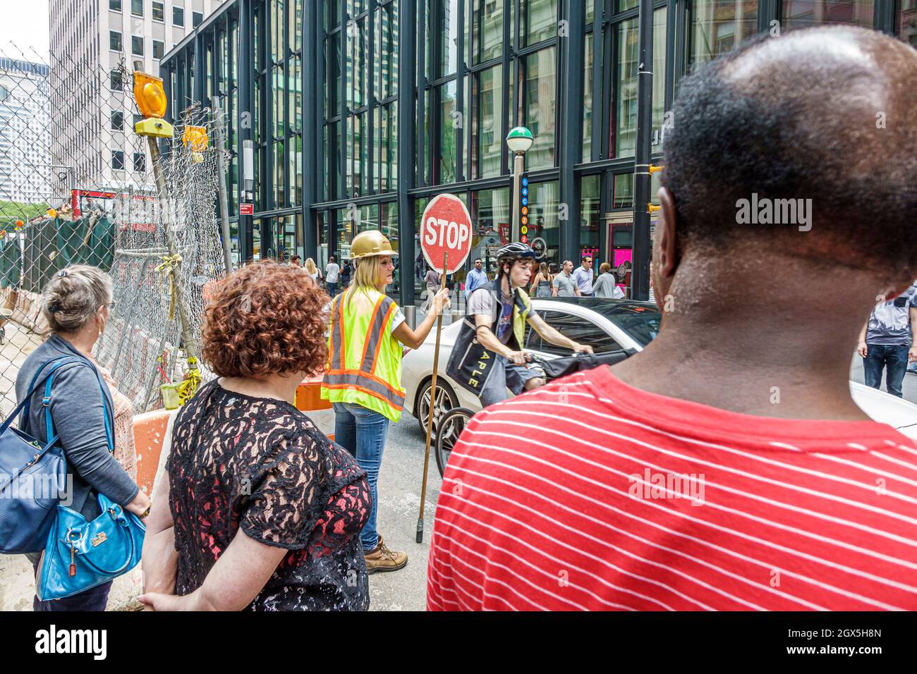 New York City, NY NYC Lower Manhattan, strada in costruzione sito pedonale attraversamento guardia del traffico, worker stop segno donna donna elmetto di sicurezza donna elmetto Foto Stock