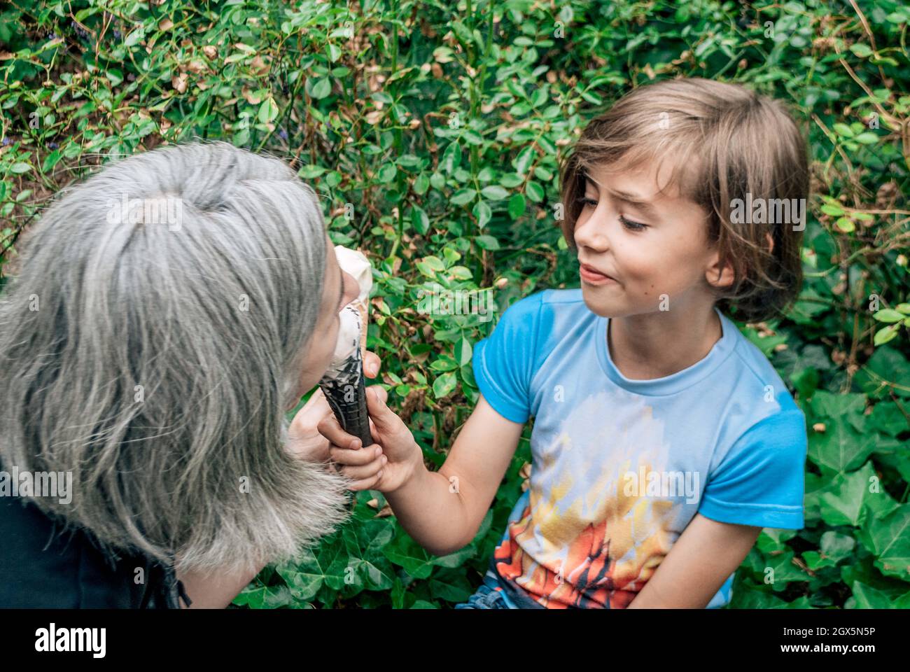 Un ragazzo tratta una donna dai capelli grigi con gelato Foto Stock