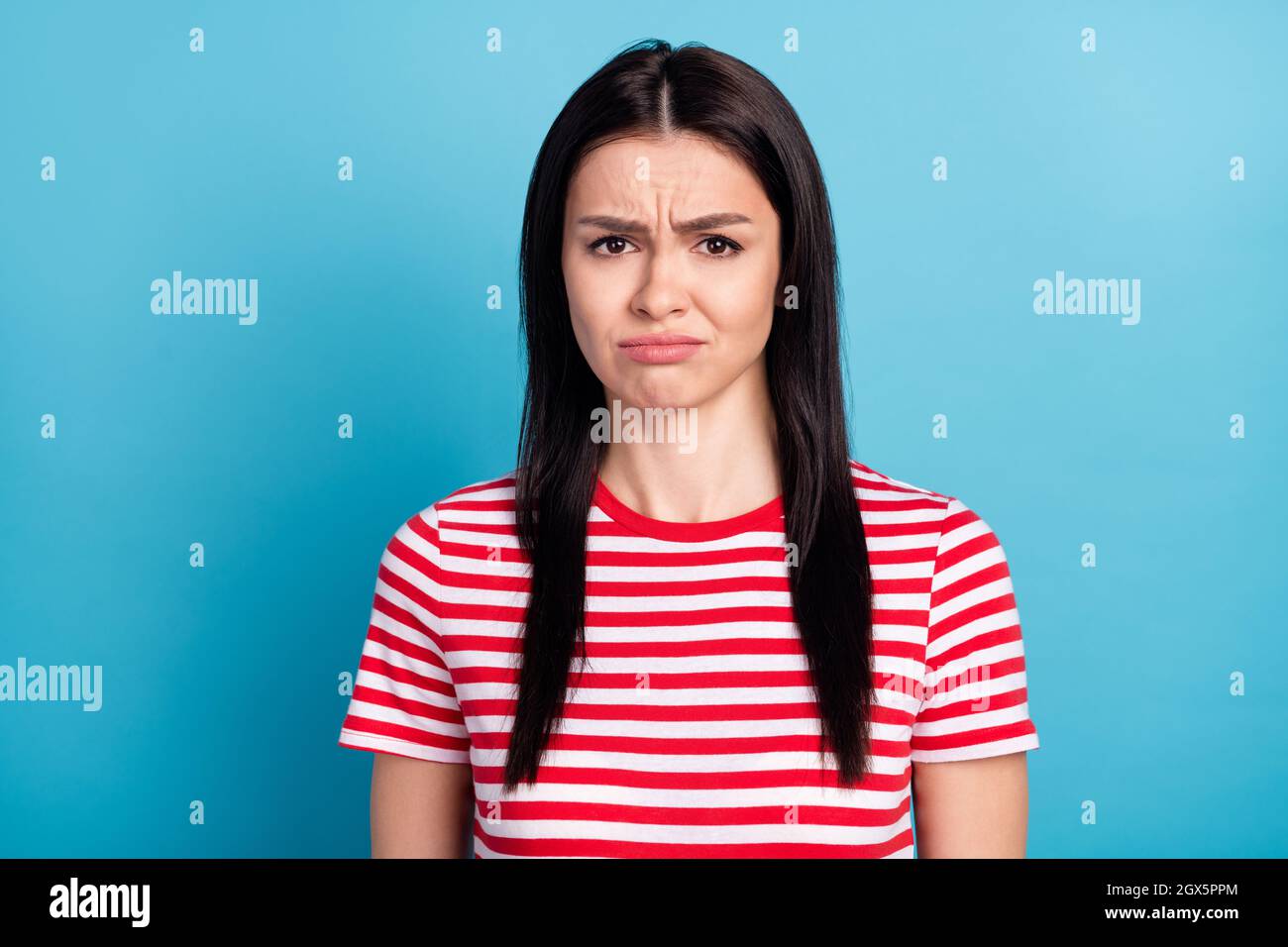 Foto di triste offesa ragazza guardare macchina fotografica indossare a righe rosso t-shirt isolato su sfondo blu colore Foto Stock