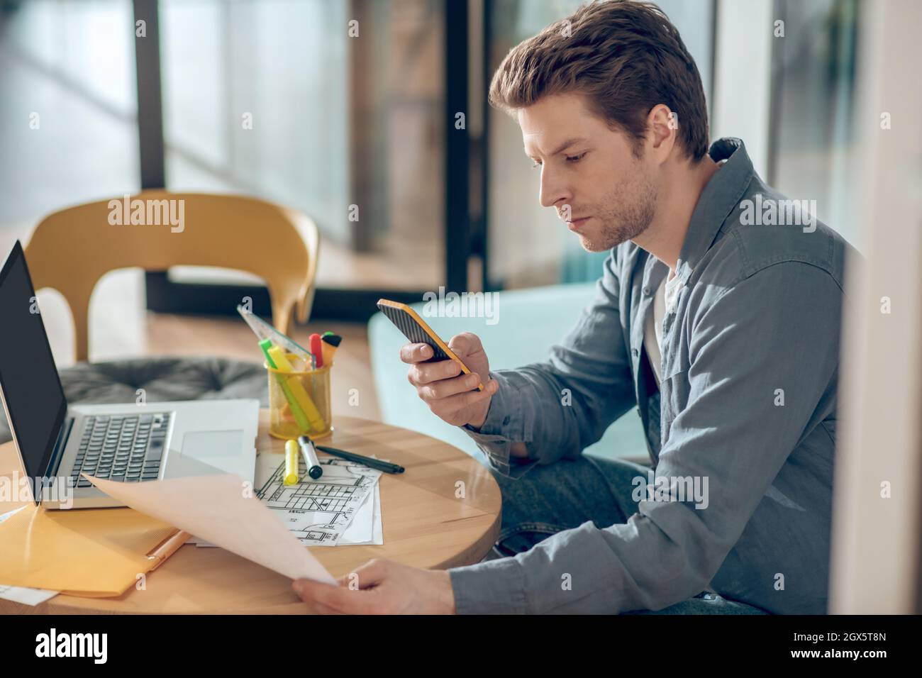Uomo con piano di costruzione che guarda lo schermo dello smartphone Foto Stock