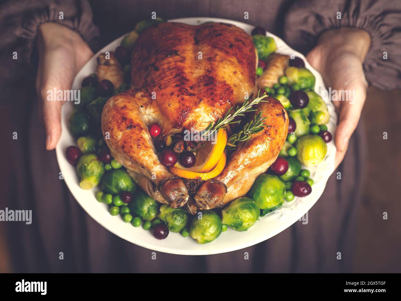 tacchino di ringraziamento o pollo per una cena di festa. Un piatto di pollo fritto nelle mani di una donna in un classico abito americano. Thanksgiving e concetto di cibo stagionale autunno. Foto di alta qualità Foto Stock
