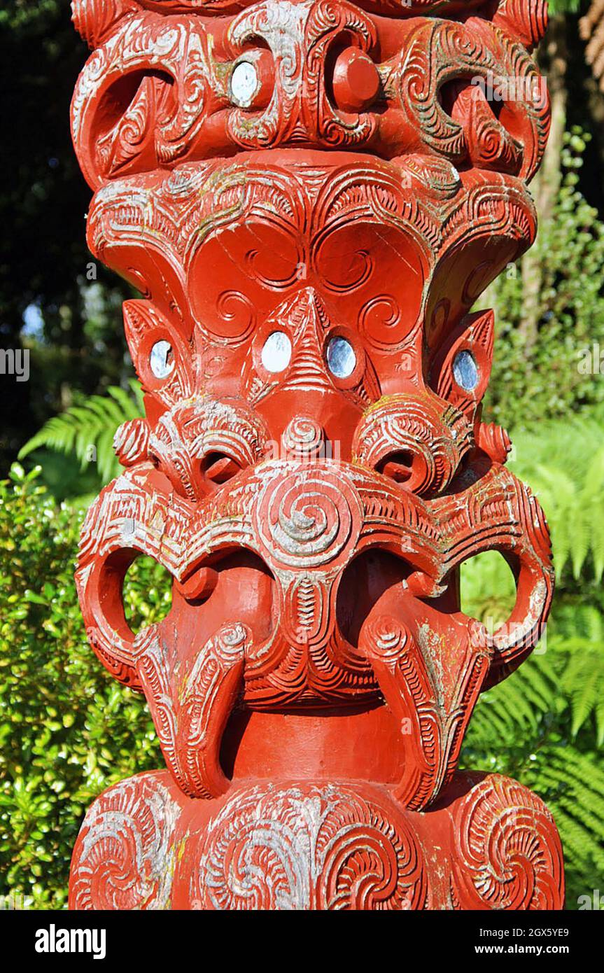 Un tekoteko Maori in legno rosso a più facce con lingue sporgenti e occhi di guscio Paua si trova a Rotorua, nuova Zelanda nel 2005. Raccontare storie attraverso l'artigianato del legno è una tradizione maori con ogni tekoteko che racconta una storia unica. Foto Stock