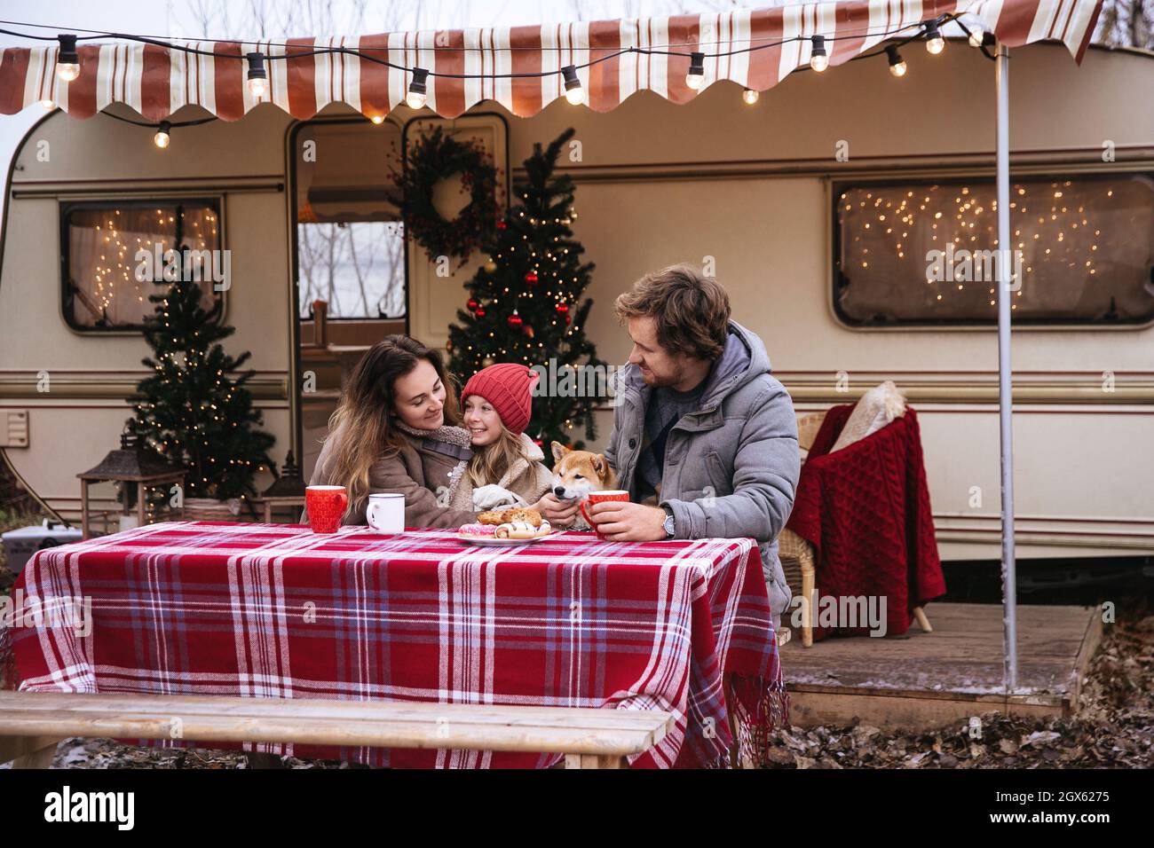 Avventura in famiglia a Natale: Mamma, papà, ragazzino e cane vivono in un rimorchio furgone per le vacanze invernali Foto Stock