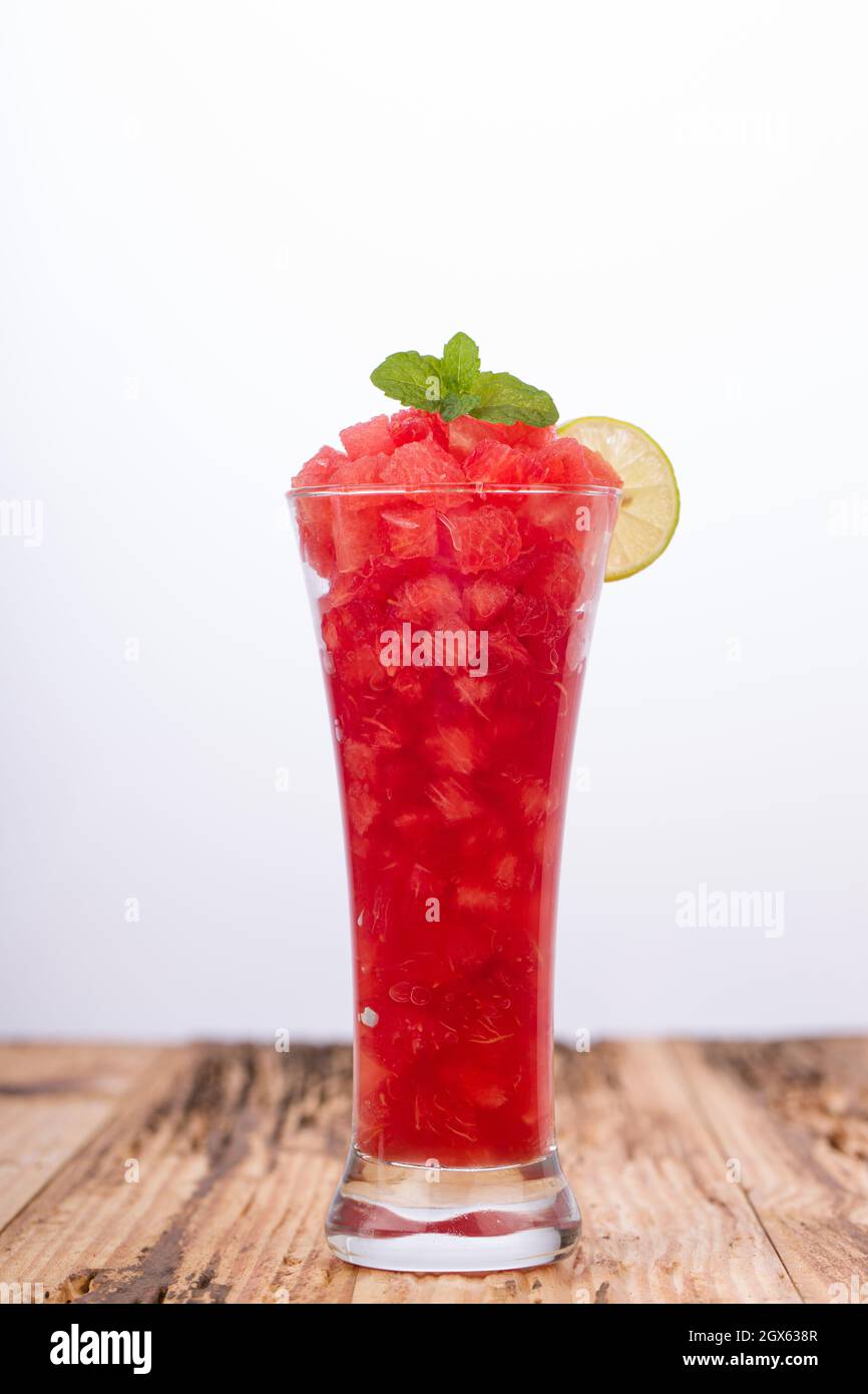 Cocomero Mojito, cocomero con limone e menta disposti in un vetro bianco trasparente su una base rustica in legno, isolato. Foto Stock