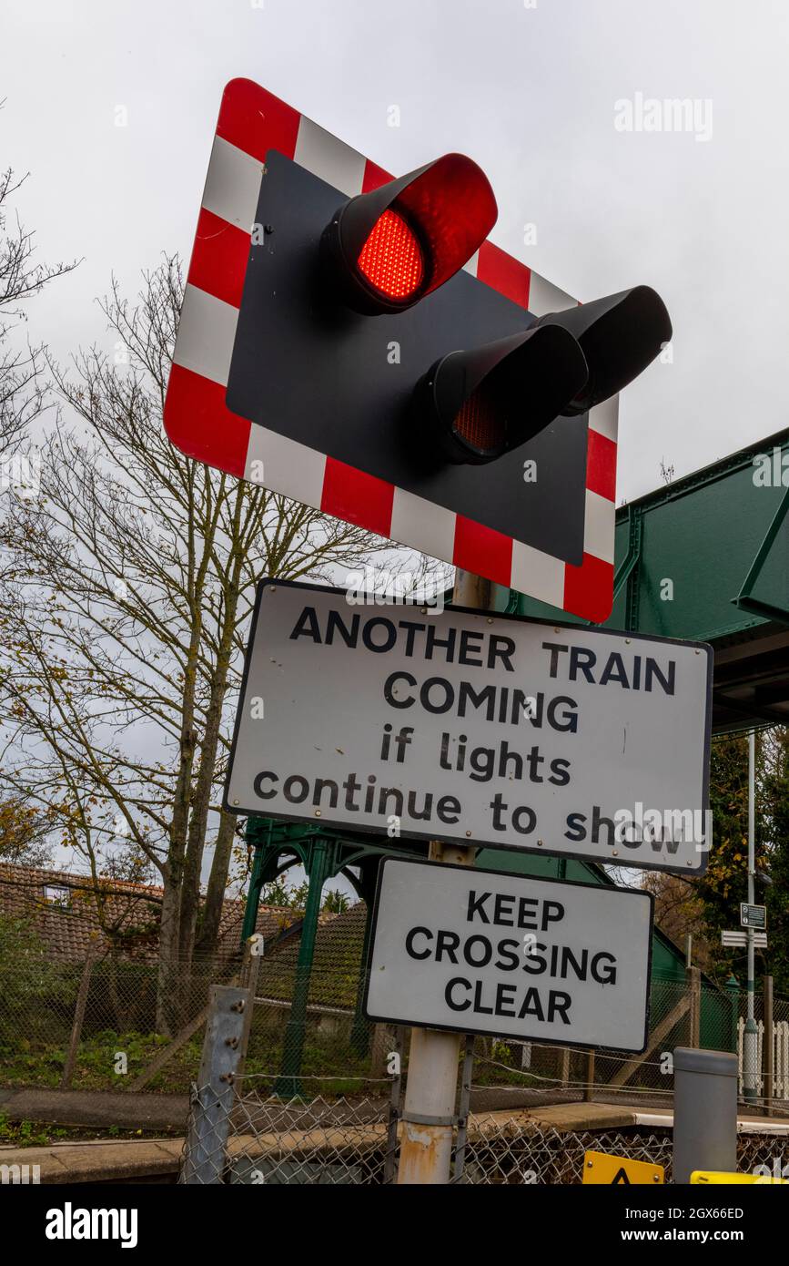 luci di segnalazione all'incrocio automatico a livello ferroviario a mezzo sbarramento con segnaletica di segnalazione di un altro treno in arrivo. a livello ferroviario che attraversa le luci lampeggianti Foto Stock