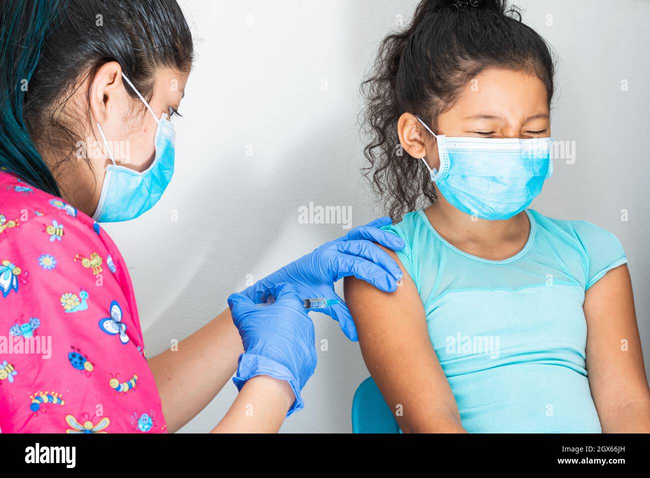 l'infermiera dei bambini che inietta il braccio di una ragazza marrone piano di vaccinazione da casa a casa, la mano del medico con guanti di gomma che inietta il vaccino covid-19. Foto Stock