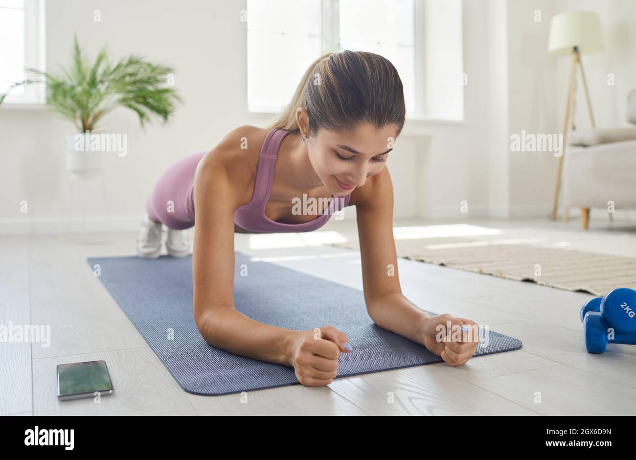 Adatta la giovane donna che fa un esercizio di asse dell'avambraccio durante il suo allenamento di idoneità a casa Foto Stock