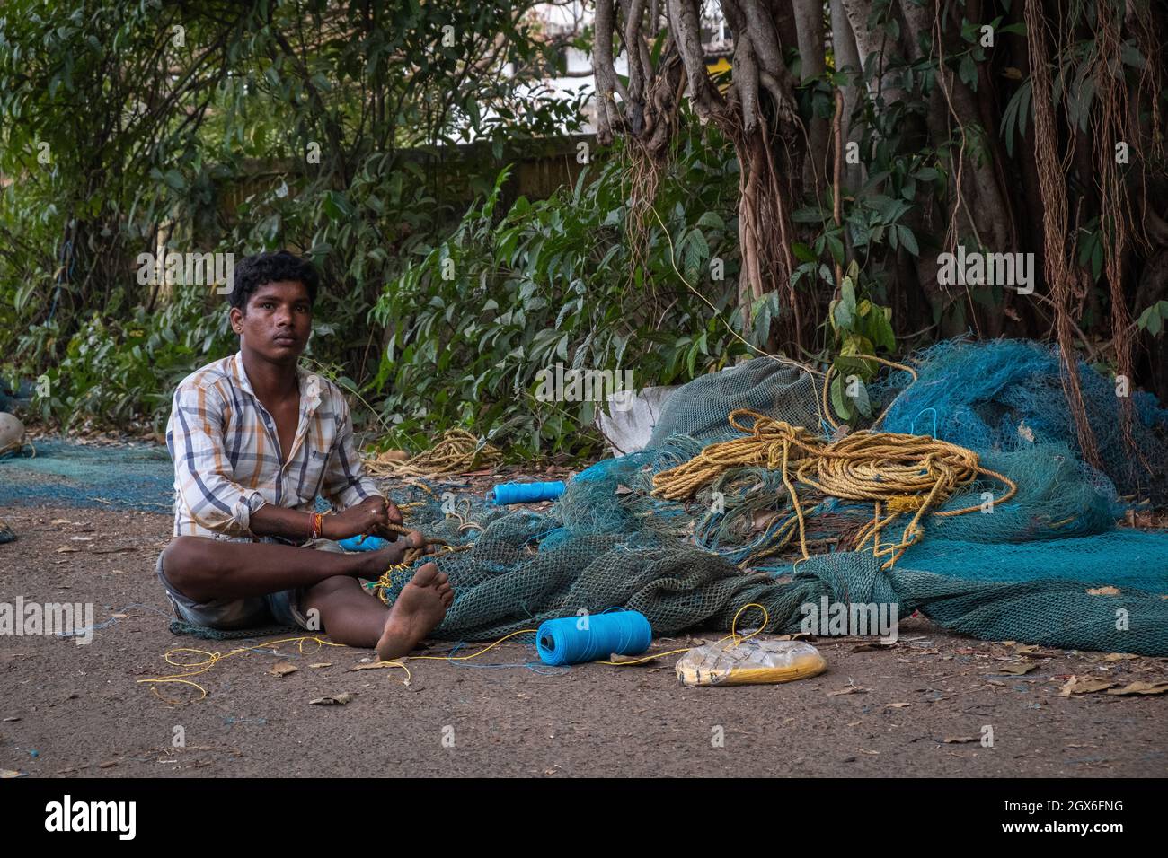 Indian Fisherman ripara la rete di pesca a Goa, India Foto Stock