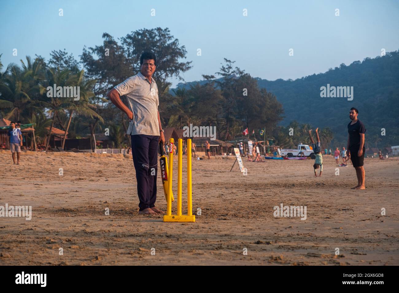 Gruppo di adulti indiani che giocano a cricket sulla spiaggia al tramonto, Goa, India Foto Stock