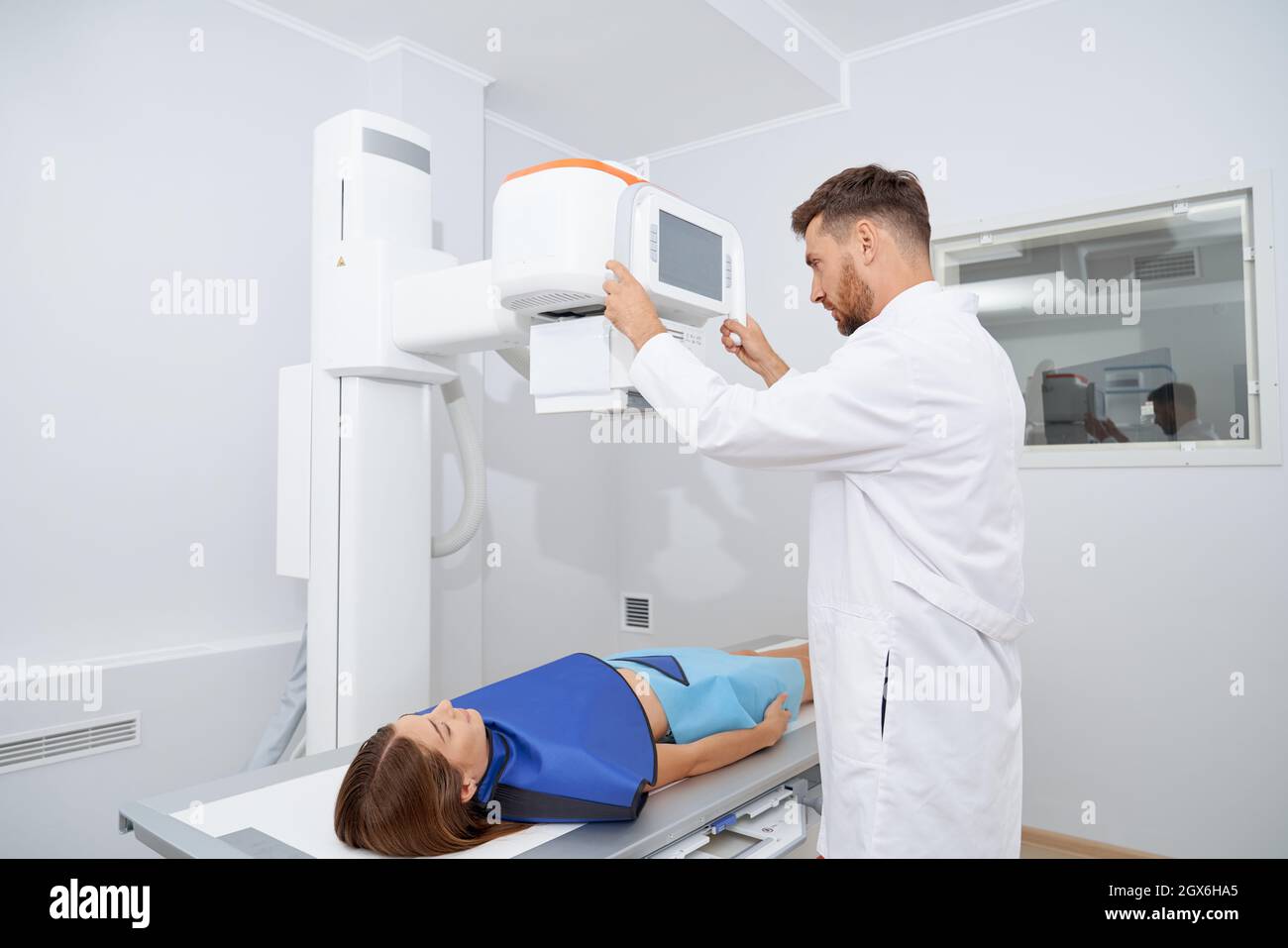 Giovane radiologo professionista che utilizza un moderno strumento a ultrasuoni per donna in accappatoio blu sicuro. Piuttosto sdraiarsi, la scansione dello stomaco su procedura di ultrasuoni. Concetto di medicina. Foto Stock